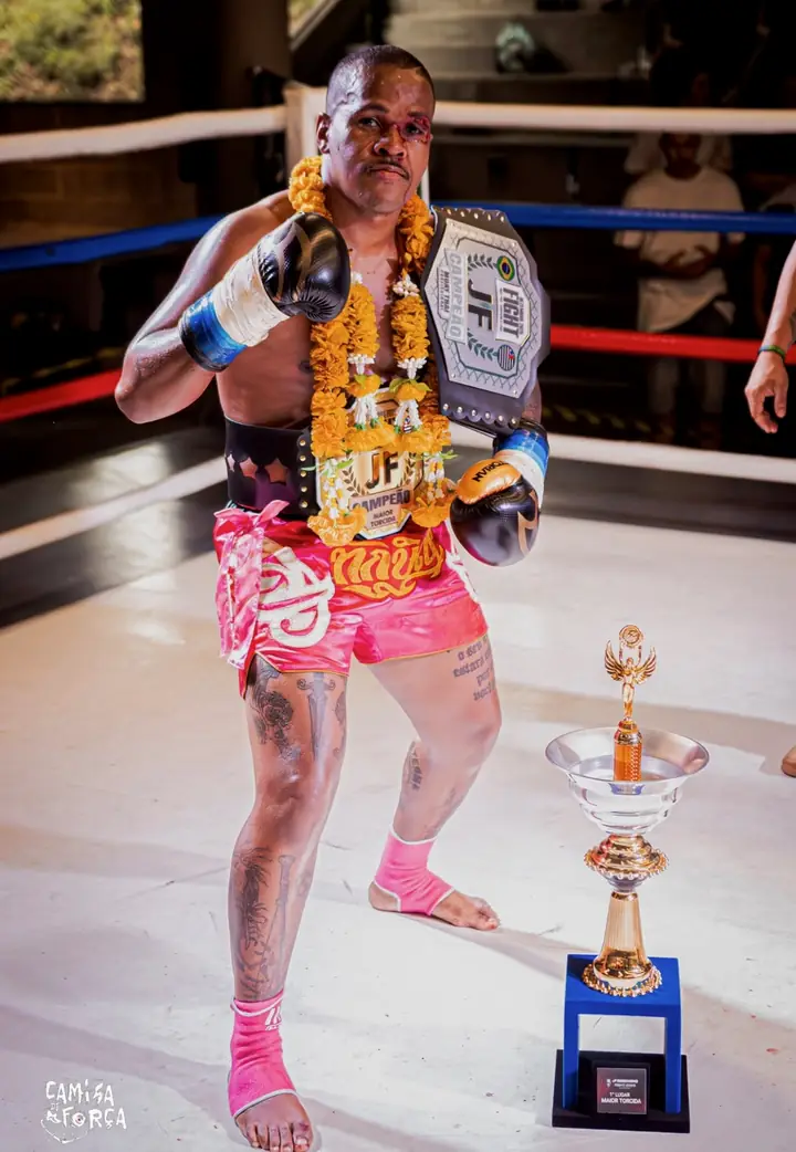 Rubens no ringue com o cinturão de campeão do JF Fight, guirlanda de flores e troféu
