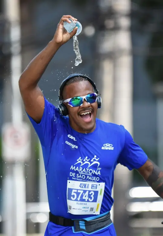 Rubens sorrindo e se refrescando com água durante a Maratona Internacional de São Paulo
